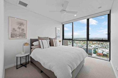 New 3 Bed Penthouse Resort style complex في بريزبين: غرفة نوم بيضاء مع سرير كبير ونوافذ كبيرة