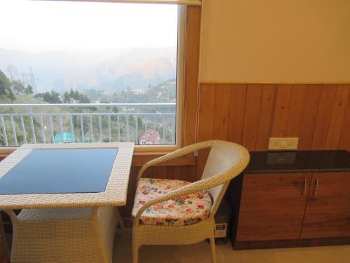 einen Tisch und Stühle mit Blick auf einen Balkon in der Unterkunft The Great Escape Homestay, Gagar, Nainital in Rāmgarh