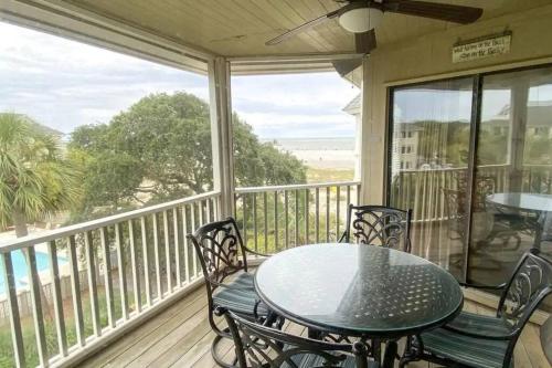 a table and chairs on a porch with a view of the ocean at Port O' Call C302 - IOP Island Retreat! Treetop Oceanview! in Isle of Palms