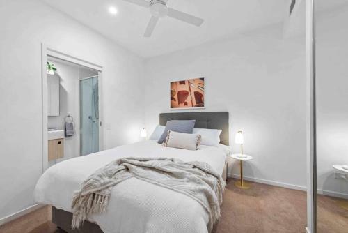 a white bedroom with a bed and a ceiling fan at Newstead Ideally Located 2bed 2Bath Free Parking in Heart of Everything in Brisbane