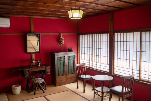 um quarto com paredes vermelhas e uma mesa e cadeiras em Machiya Guest House Carta em Kanazawa