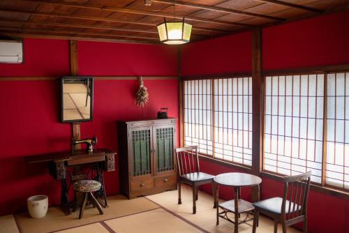 a room with red walls and a table and chairs at Machiya Guest House Carta in Kanazawa