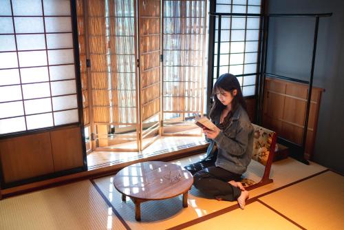 a woman sitting in a room looking at her cell phone at Machiya Guest House Carta in Kanazawa