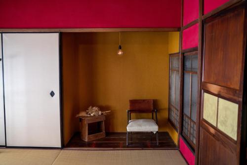 a room with a door and a chair and a table at Machiya Guest House Carta in Kanazawa