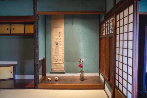 a room with a vase with flowers in it at Machiya Guest House Carta in Kanazawa