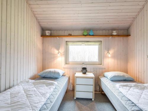 two beds in a small room with a window at Holiday Home with Spa & Sauna in Oksbøl