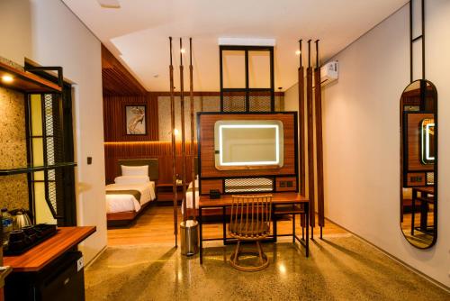 um quarto com uma televisão, uma secretária e uma cama em Nata Azana Hotel Solo em Surakarta