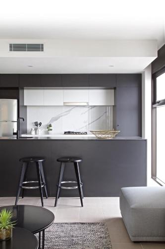 a kitchen with black and white cabinets and stools at Opera Apartments South Brisbane in Brisbane