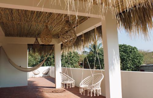 a porch of a resort with chairs and a hammock at Casa Luni in Puerto Escondido