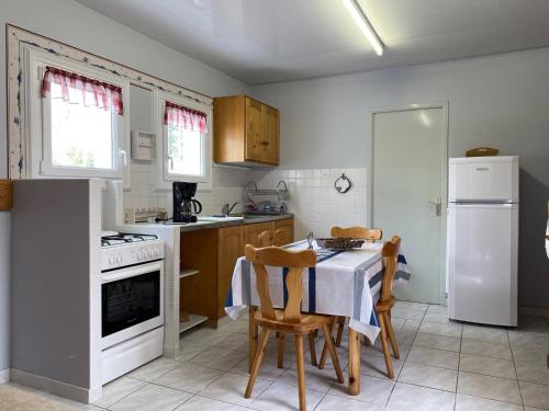 La cuisine est équipée d'une table et de plaques de cuisson blanches. dans l'établissement Charmante Maison avec Jardin et Parking Privé, à 4 km de la Plage - Idéalement Située à Erdeven - FR-1-397-70, à Erdeven