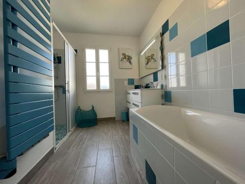 baño con bañera blanca y azulejos azules en Maison Saint-Denis-d'Oléron, 6 pièces, 10 personnes - FR-1-246A-226 en Saint-Denis-dʼOléron