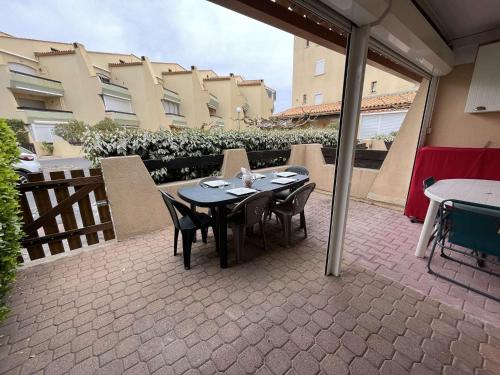 un patio avec une table et des chaises et un bâtiment dans l'établissement Accès direct plage, appartement 2 pièces avec terrasse, parking et Wi-Fi optionnel. - FR-1-387-193, à Marseillan