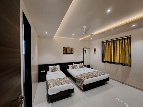 a bedroom with two beds and a window at Bouquet Residency in Nashik