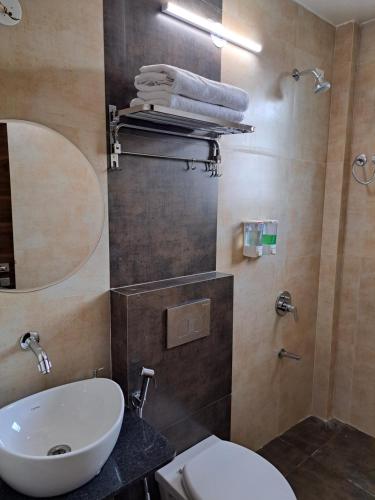 a bathroom with a sink and a toilet and a mirror at Bouquet Residency in Nashik