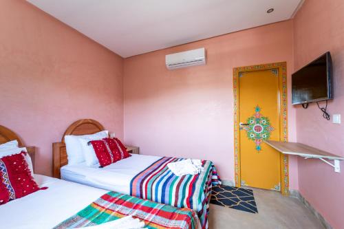 a room with two beds and a yellow door at Riad Les Nuits De Fès in Fès