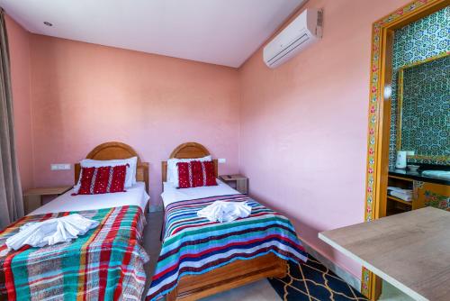 two beds in a room with pink walls at Riad Les Nuits De Fès in Fès