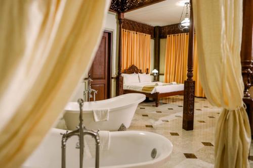 a bathroom with a tub and a sink and a bed at Las Casas Filipinas de Acuzar in Bagac
