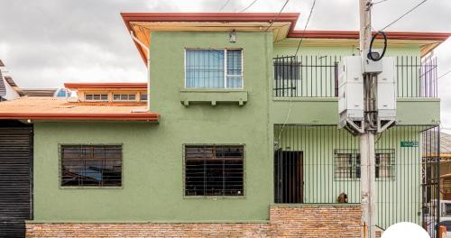 a green building with windows and a dog in front of it at Casa Pitahaya in San José