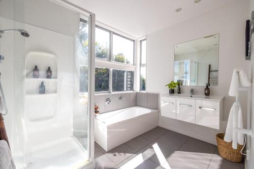 un bagno bianco con vasca e grande specchio di Bellevue a Onetangi