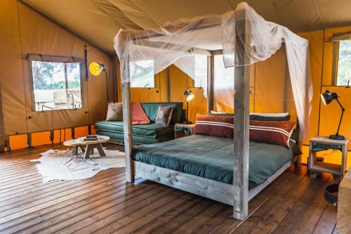 a bedroom with a canopy bed and a couch at Glamping 148 Tasmania in St Helens