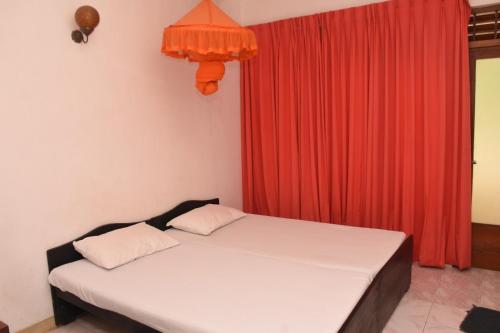 a bedroom with a bed with a red curtain at Mount Crest Inn Deniyaya in Deniyaya