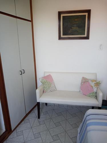 a room with a white bench and a painting at Quartos Prox Engenhão e Norte Shopping in Rio de Janeiro