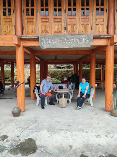 a group of people sitting at a table in a pavilion at Xuân nghi homestay in Yen Bai