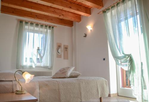 a white bedroom with a bed and a window at Agritur de Poda Apartments in Flavon