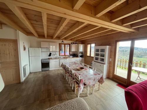 a kitchen with a table with chairs and a large window at Chalet des Monts Dore in Chastreix