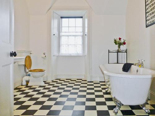 a bathroom with a white tub and a checkered floor at The Factors House - 25752 in Kilmartin
