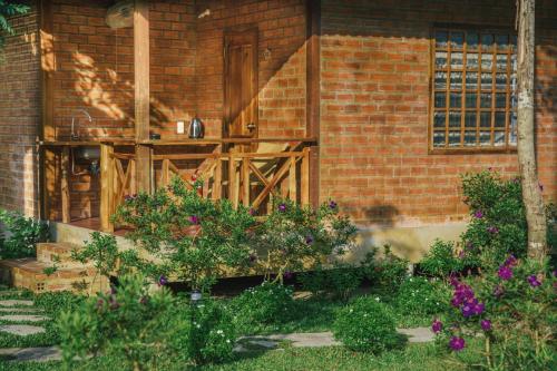 a brick house with a wooden porch with flowers at Phu Quoc Valley Sen Bungalow in Phu Quoc