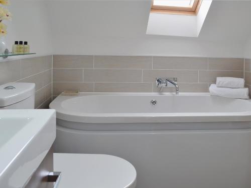 a white bathroom with a tub and a toilet at Dairy Cottage in Matfield