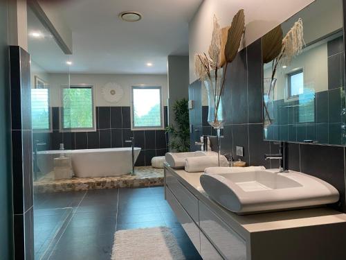 ein großes Bad mit einer Badewanne und einem Waschbecken in der Unterkunft The Palm - Beachside Home with Heated Pool & Cinema in Mudjimba