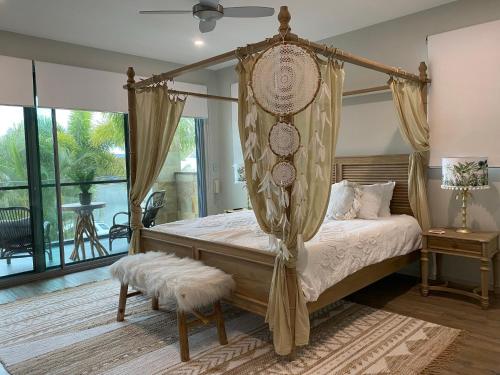 a bedroom with a canopy bed and a balcony at The Palm - Beachside Home with Heated Pool & Cinema in Mudjimba