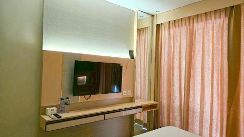 baño con TV y espejo en Nagoya thamrin apartment (Favehotel Building) en Nagoya