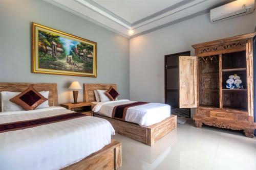 een slaapkamer met 2 bedden en een schilderij aan de muur bij Asli Bali Villas in Bangli