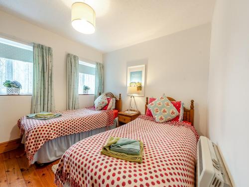 een slaapkamer met 2 bedden met rode en witte lakens bij Ty Cae Mawr - Oad in Gowerton