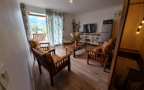 a living room with chairs and a table and a television at Chambre d'hôte Les Amoureux du Cirque in Cilaos