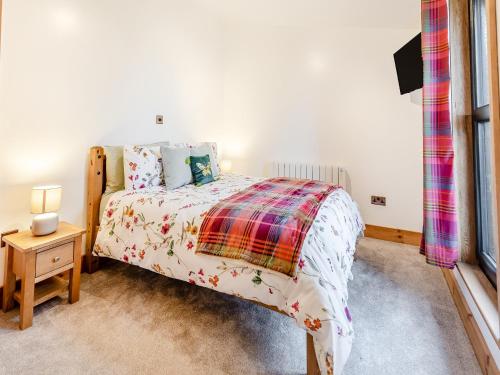 a bedroom with a bed with a plaid blanket at Piglets House - Uk43488 in Aldington