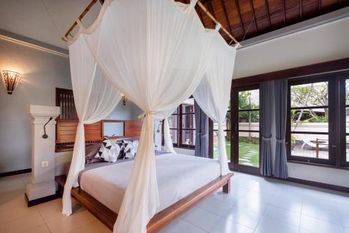 a bedroom with a canopy bed with white drapes at Villa Santai Pemuteran in Pemuteran