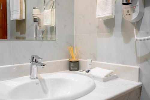 a white bathroom with a sink and a mirror at Damask Resort in Jabal Al Akhdar