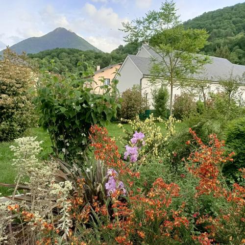 a garden with flowers and a house in the background at Le balcon des cimes in Adast