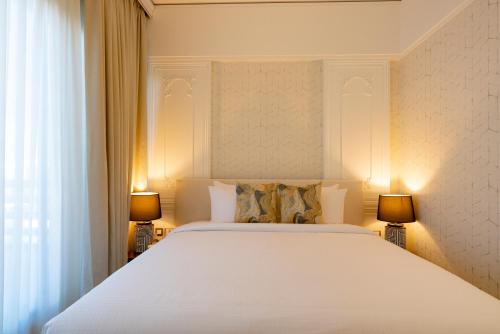 a bedroom with a large white bed with two lamps at Damask Resort in Jabal Al Akhdar