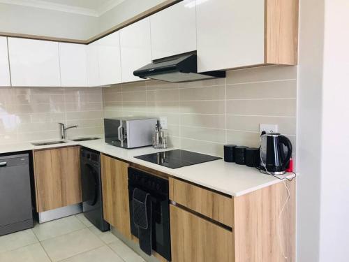 a kitchen with white cabinets and a black appliance at Luxury beach lagoon 1 Bedroom apartment in Pretoria