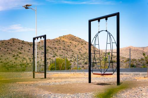 two swings in a field with mountains in the background at Damask Resort in Jabal Al Akhdar