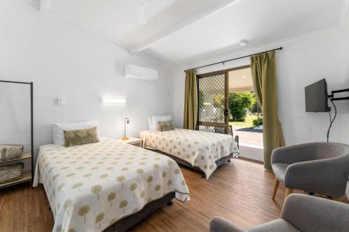 a hotel room with two beds and a chair at Kinka Palms Motel in Yeppoon