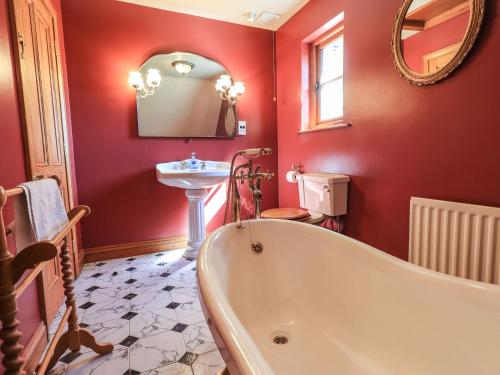 a red bathroom with a tub and a sink at The Stables in Ambleside