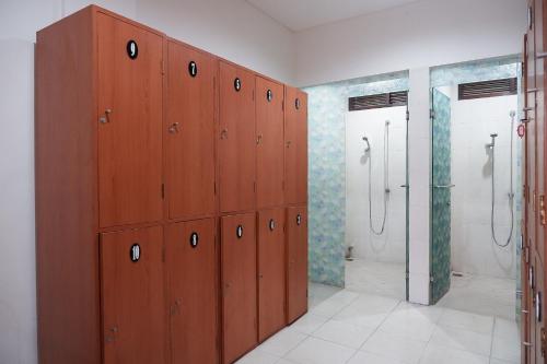 a bathroom with wooden cabinets and shower stalls at Hippo Diving Bali Rooms in Sanur