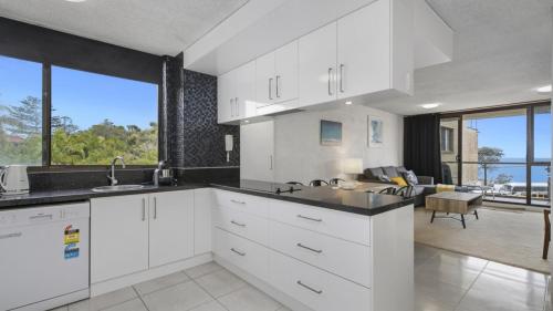 een keuken met witte kasten en een groot raam bij Beachpark Apartments - Close To Beach in Port Macquarie