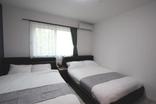 dwa łóżka w pokoju z oknem w obiekcie TEINE WHITE HOUSE w mieście Sapporo